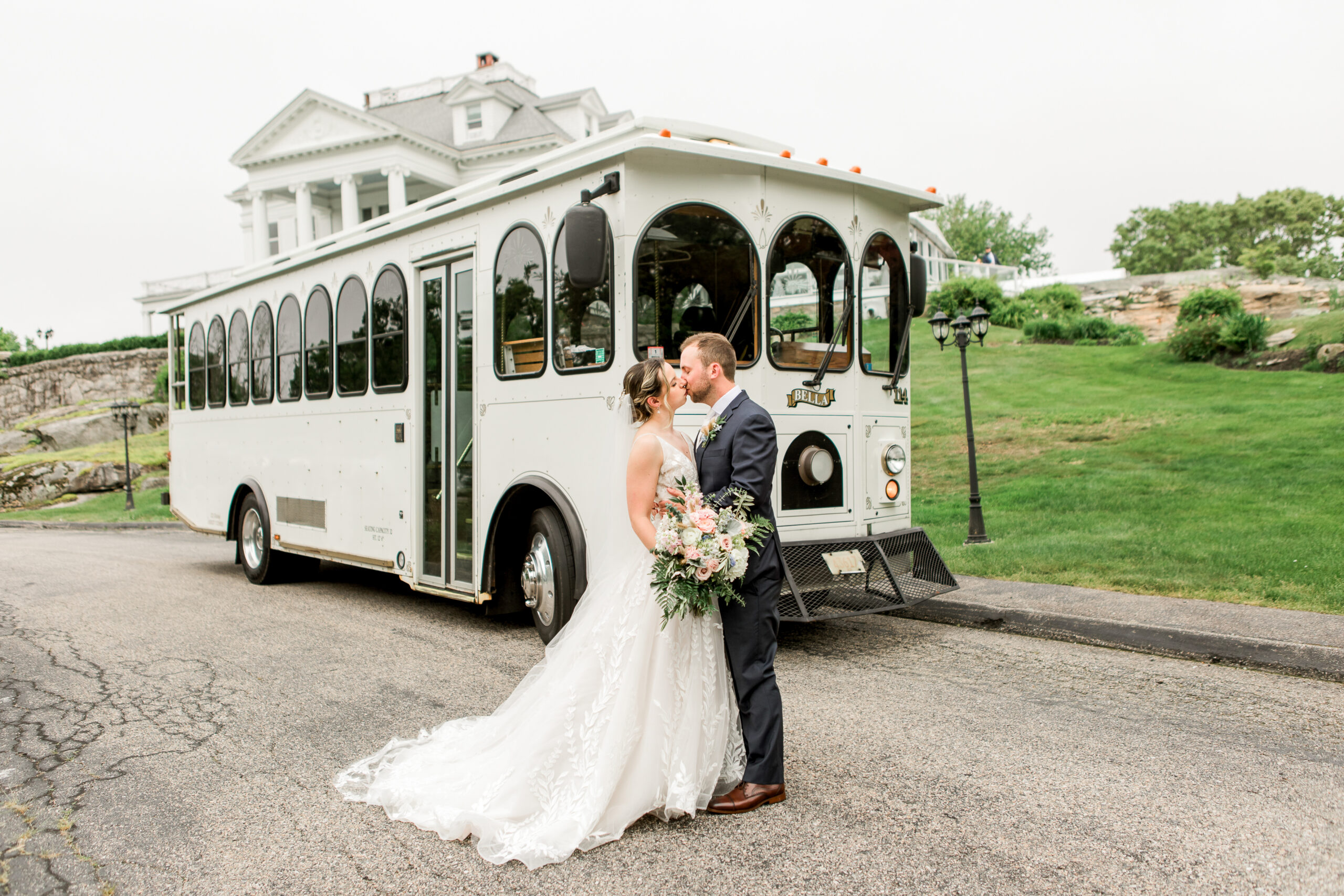 Bride and groom kissing in front of trolley with haley mansion in the background
